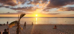a group of people on a beach at sunset at Nayuha Beach New Penthouse B3 in Flic-en-Flac