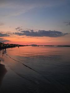 a sunset on a beach with the water at Lilli & Evoque Apartments in Civitanova Marche