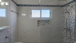 a white bathroom with a shower and a window at Cozy Private Apartment Calheta in Arco da Calheta