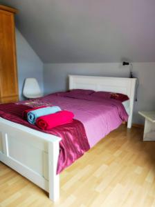 ein weißes Bett mit lila Laken und einer rosa Decke in der Unterkunft Cichy Zaułek Górki Wielkie in Górki Wielkie