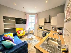 a kitchen and living room with a blue couch in a room at Sensational Stay- Fountainbridge in Edinburgh