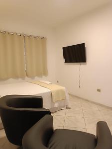 a bedroom with a bed and a tv on a wall at UniqueFlats - Casa Mosaico in Nova Iguaçu