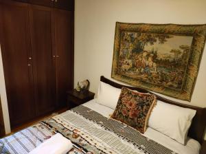 a bedroom with a bed with a tapestry on the wall at Villa Erotokritos in Palaios Agios Athanasios +14 photos