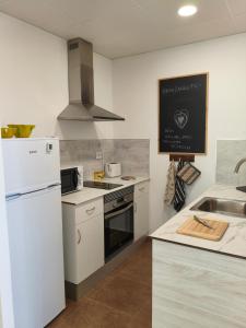 a kitchen with a white refrigerator and a sink at L'àtic dels flamencs in Sant Jaume d'Enveja
