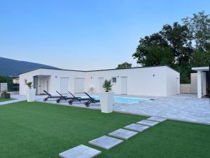 a white building with a pool and green grass at Casa La Familia in Posušje