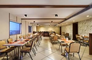 a restaurant with tables and chairs in a room at Astoria Hotels Madurai in Madurai