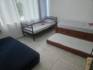 a room with two beds and a chair and a window at Residencial Dois58 in Niterói