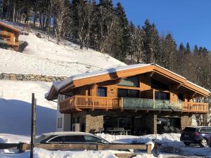 a log cabin with a car parked in the snow at Chalet Mühlbach near Hochkönig Ski Lift in Mühlbach am Hochkönig