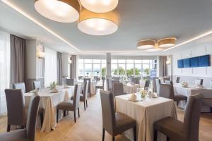 a restaurant with white tables and chairs and windows at Miramar Suites in Sada