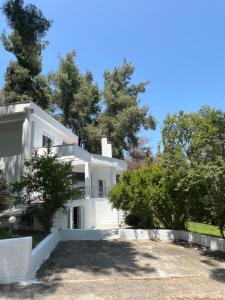 a white house with trees in the background at Villa Angie in Sani Beach +43 photos