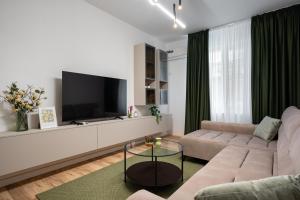 a living room with a couch and a flat screen tv at Rossini King bed i BR Apartment in Bucharest