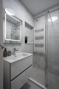 a white bathroom with a sink and a shower at Rossini King bed i BR Apartment in Bucharest