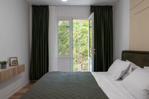 a bedroom with a bed with green curtains and a window at Rossini King bed i BR Apartment in Bucharest