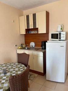 a small kitchen with a white refrigerator and a microwave at Milchevi Guesthouse in Sozopol +30 photos