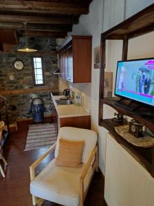 Una sala de estar con un televisor de pantalla plana en una pared. en Villa Aretousa, en Palaios Agios Athanasios