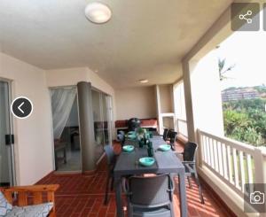 a room with a table and chairs on a balcony at Laguna la crete 45,Uvongo in Uvongo Beach