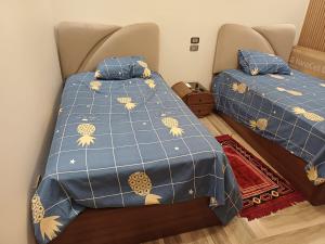 a bedroom with two beds with blue comforter at Luxury appartment New Cairo in New cairo