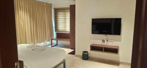 a hotel room with a bed and a flat screen tv at Hotel Amulya Royal Inn in Bangalore