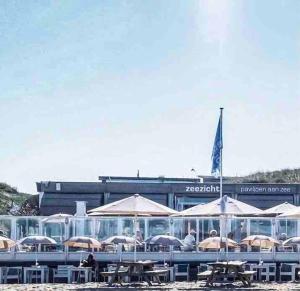 a group of tables with umbrellas in front of a building at Appartement Buissant des Amorie! in Castricum