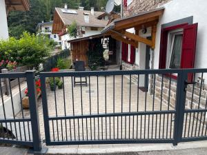 a black fence in front of a house with a red door at Appartamento Pineta casa vacanze Sci & Natura in Varena