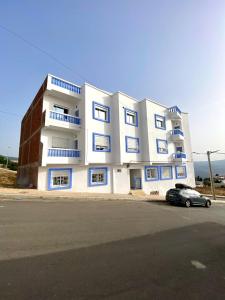 a white building with blue windows and a car parked in front at Casa almas in Chefchaouen