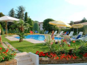 a woman standing next to a swimming pool with chairs and umbrellas at Holiday Home in Lazise near Lake Garda in Lazise +32 photos