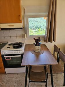 a kitchen with a table and a stove and a window at Magafinis Apartment in Prinos