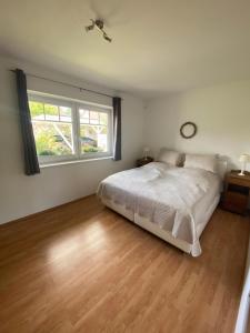 a white bedroom with a bed and a window at Ruhige, gemütliche Ferienwohnung in Herzen der Lüneburger Heide in Kirchgellersen