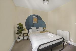 a bedroom with a large bed with a blue headboard at Luxe Ami Beh Large Group Apartment by PolkaStays in Blackpool +37 photos