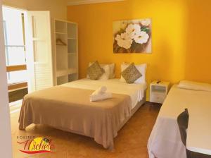 a bedroom with two beds and a painting on the wall at Pousada Michele in Morro de São Paulo