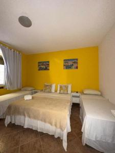 a bedroom with two beds and a yellow wall at Pousada Michele in Morro de São Paulo +77 photos
