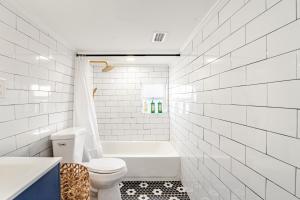 a white bathroom with a toilet and a bath tub at Southern Charm & Modern Comfort in Jacksonville +97 photos