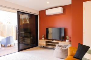 a living room with an orange accent wall at CBD 2 Bed 2 Bath Luxury Gem With Free Car Park in Christchurch