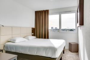 Una habitación de hotel con una cama y una ventana. en The Originals City, Hôtel Caen Mémorial, en Caen