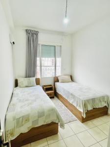 Un dormitorio con dos camas y una ventana. en Cozy apartment, in secure residence, en Agadir