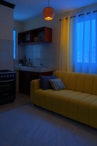 a living room with a yellow couch and a kitchen at Delta shop house in Mombasa