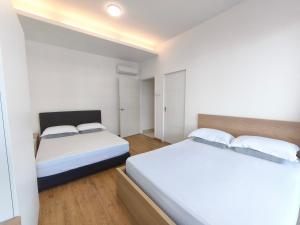 two beds in a bedroom with white walls and wooden floors at Prmium 2 Bedroom Apartment D in Sibu