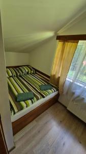 a small bed in a room with a window at Cabană în inima munților 2 - Gálkuti Kulcsosház in Bălan