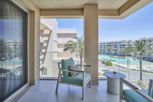 un balcon avec une chaise et une vue sur la piscine dans l'établissement Marassi Boutique Hotel-Vela Suites, à El Alamein