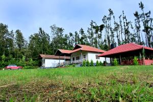 a house with a red roof in a field at Siri Kuteera Homestay in Chikmagalūr