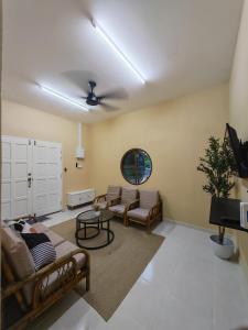 a living room with couches and a ceiling fan at GreenAcres Cottage in Pasir Puteh +14 photos