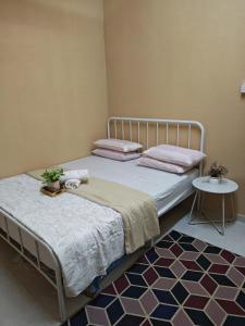 a bedroom with two beds and a rug at GreenAcres Cottage in Pasir Puteh