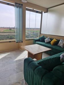 a living room with a green couch and a table at Bel appartement pour location in O Ben Slimane