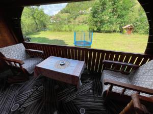 a porch with a table and chairs and a playground at Cabana trei paltini in Poiana Vadului