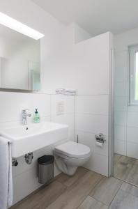 a white bathroom with a sink and a toilet at GLEUEL INN HOTEL - Serviced Apartments in Hürth