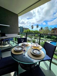 a table with plates and wine glasses on a balcony at Luxuoso e sofisticado Beach Class Summer by HM in Porto De Galinhas +208 photos
