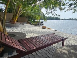 un banco de madera sentado junto a un cuerpo de agua en Aqua Leisure Resort Bentota, en Bentota