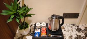 a tea kettle on a counter next to a potted plant at Hotel Shlok Inn in Somnath