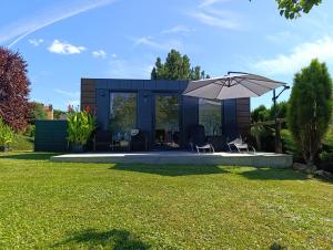 a blue house with chairs and an umbrella at TINY HOUSE mezi sklepy in Kobylí