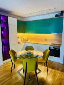 a kitchen with a table and green chairs at Citysmart Apartment in Tuzla